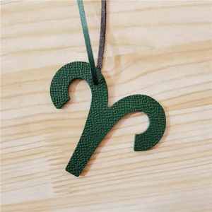 Vue détaillée du charm de sac zodiaque Bélier en cuir vert foncé, accessoire élégant pour voiture.
