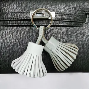 Detail shot of the two-tone leather tassel bag charm keychain with metal ring accessory.
