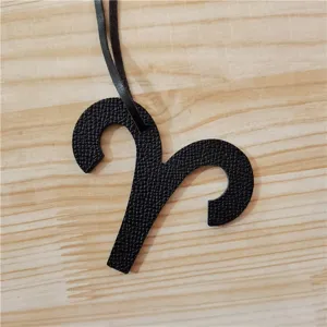 Gros plan détaillé du pendentif de sac en cuir noir signe astrologique Bélier texture et forme.