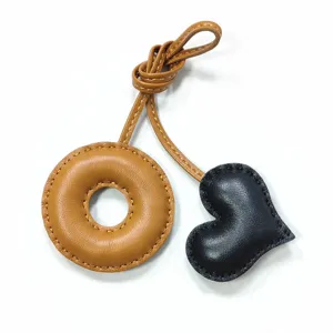 Handmade leather donut and heart bag charm, exquisite stitching, stylish accessory.