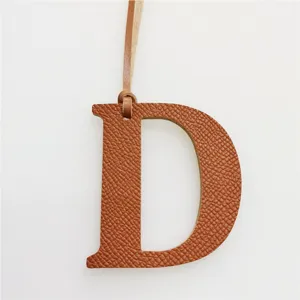 Detail view of a stylish leather letter D bag charm with hanging strap, elegant accessory.