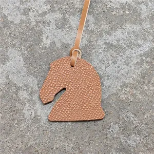 Gros plan détaillé du mini charm de sac tête de cheval en cuir avec texture fine.