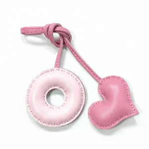 Pink leather bag charm with donut shape and heart pendant, handmade stitching accessory.