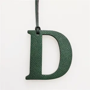 Dark green leather letter D bag charm detail, luxury style handbag accessory pendant.