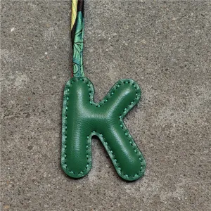 Grüner Leder Buchstabe K Taschenanhänger mit stilvollem botanischen Seidenband Accessoire.