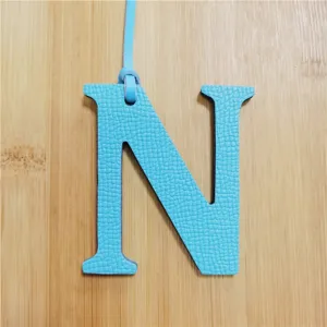 Light blue leather letter N bag charm with hanging strap, stylish fashion accessory for women.
