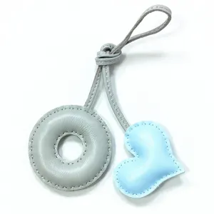 Handmade leather bag charm with grey donut and light blue heart shape, stylish accessory.