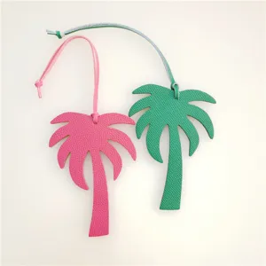 Close-up detail shot of stylish leather palm tree bag charms in vibrant pink and green colors.