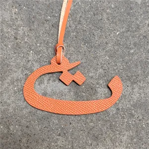 Orange leather Arabic letter bag charm pendant, stylish handbag accessory for women.