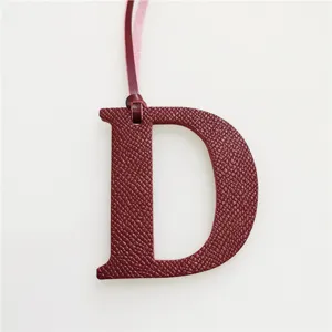 Burgundy leather letter D bag charm with hanging strap, elegant luxury style accessory.