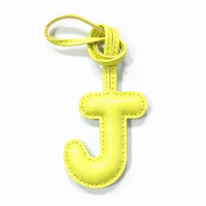 Yellow leather letter J bag charm, alphabet keychain pendant detail view for personalized gifts.