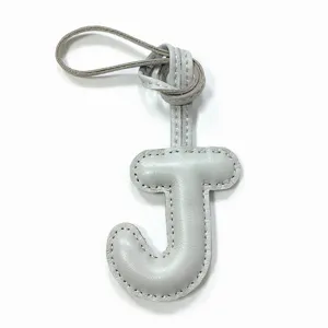 Close-up detail of grey leather letter J bag charm with stitching and leather strap loop.