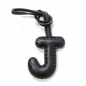 Black leather letter J bag charm close-up detail showcasing fine stitching and knot design.