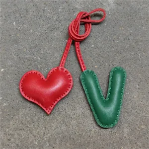 Primer plano detallado del dije de bolso de cuero hecho a mano con corazón y letra V.