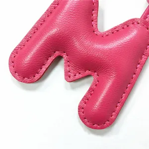 Detailaufnahme eines rosa Leder Buchstaben M Taschenanhängers mit besonders feiner Naht.