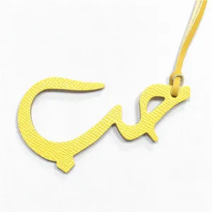 Détail de breloque de sac en cuir jaune avec lettre arabe, pendentif élégant.