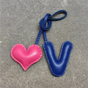 Primer plano detallado del colgante de bolso de cuero con corazón y letra V y costura artesanal.