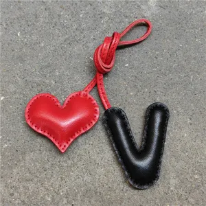 Colgante de bolso de cuero hecho a mano con corazón rojo y letra V negra para accesorios.