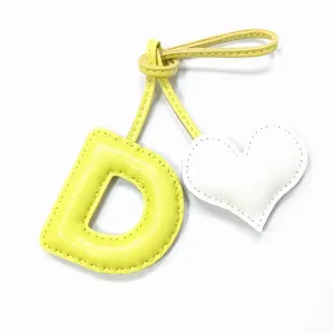 Handmade yellow letter D leather bag charm with white heart pendant for purse accessories.