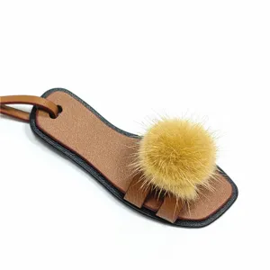 Nahaufnahme des niedlichen Mini-Sandalen-Taschenanhängers mit weichem Nerzfellball und Lederriemen.