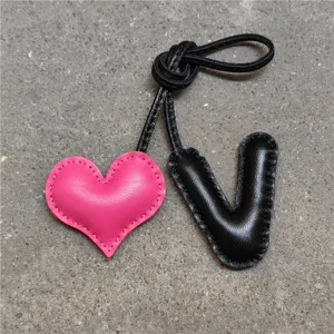 Vista detallada en primer plano del colgante de bolso de cuero artesanal con corazón rosa.