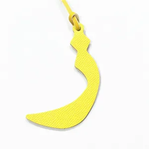 Yellow leather bag charm featuring a crescent Arabic letter design with a thin strap.