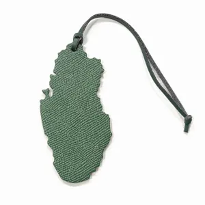 Vue detaillee du pendentif de sac en cuir en forme de carte du Qatar avec laniere verte.