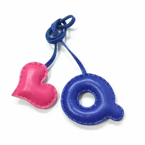 Nahaufnahme des handgefertigten Leder-Taschenanhängers mit pinkem Herz und blauem Q.