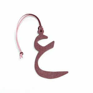 Detailed close-up of the burgundy leather Arabic letter bag charm with a pink strap.