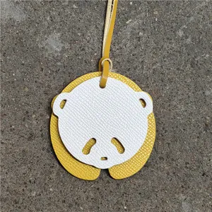 Gros plan détaillé du charm de sac en cuir panda mignon, pendentif mini sac avec lanière jaune.