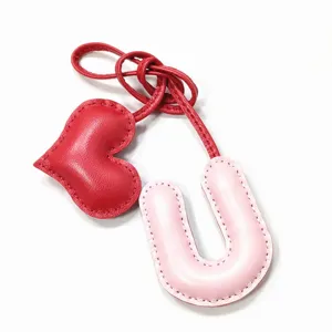 Leder Buchstabe U und Herz Taschenanhänger Detail mit Handnähte in rot und rosa Farben.