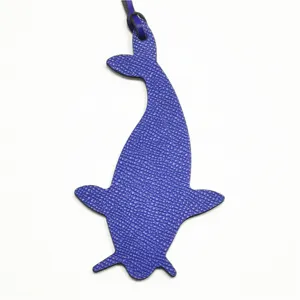 Detalle de dije de bolso de ballena de cuero azul con textura fina y correa colgante.