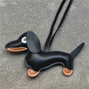 Gros plan détaillé du charm de sac en cuir de teckel mignon avec sa lanière noire élégante.