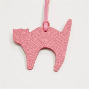 Close-up detail of the pink leather cat bag charm, showing fine texture and strap.