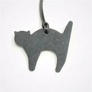 Close-up detail view of the dark grey leather cat bag charm, featuring fine texture.