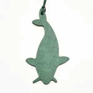 Detalle del colgante de bolso de cuero con forma de ballena verde y correa.