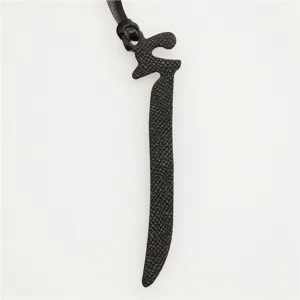 Black leather Arabic letter bag charm detail close-up, premium texture key ring pendant.