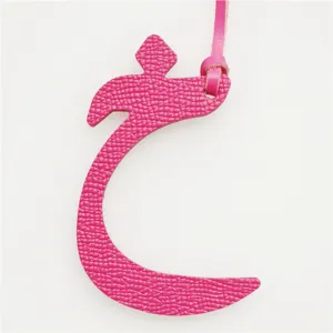 Close-up detail of the hot pink leather Arabic letter bag charm, showing fine texture and loop.