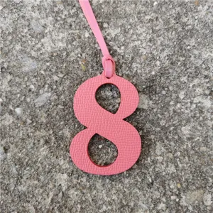 Close-up detail of the pink leather number 8 bag charm pendant, showing fine leather texture.