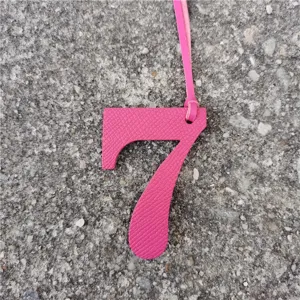 Dettaglio ciondolo borsa numero 7 in pelle rosa, elegante accessorio fai da te con cinturino.