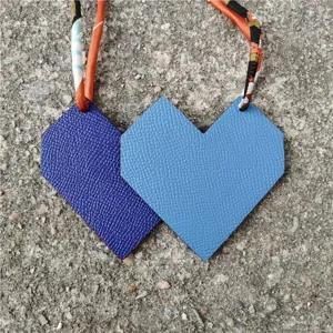 Detailed shot of double-colored leather heart bag charm with silk ribbon strap pendant.