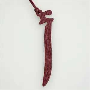 Burgundy leather Arabic letter bag charm, stylish purse accessory and car key pendant detail.