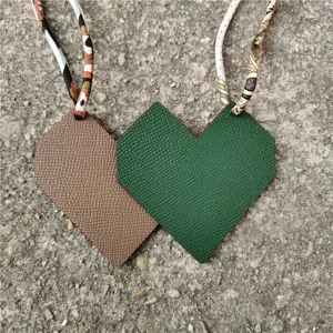 Heart-shaped leather bag charm with silk ribbon strap, dual-color handbag accessory.