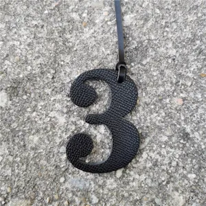 Close-up view of a black leather texture number three bag charm pendant detail shot texture.