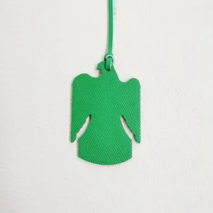 Detalle de dije de bolso de pájaro de cuero verde, colgante animal para bolsos y accesorios.
