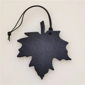 Detailed view of black leather maple leaf bag charm, elegant car pendant accessory for stylish daily use.