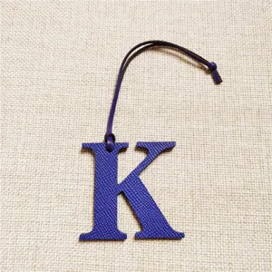 Détail de charm de sac lettre K en cuir bleu, accessoire élégant pour sac à main monogramme.