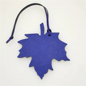 Blue leather maple leaf bag charm detail view, chic purse pendant or car hanging decoration.
