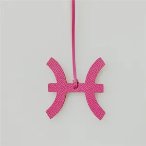 Detailopname van roze lederen Vissen sterrenbeeld tasbedel hanger met elegante textuur.
