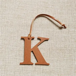 Détail de breloque de sac lettre K en cuir marron avec texture Epsom et lanière.
